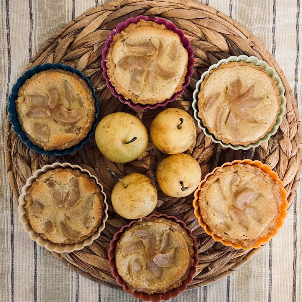 six small Asian pear tarts around four fresh Asian pears